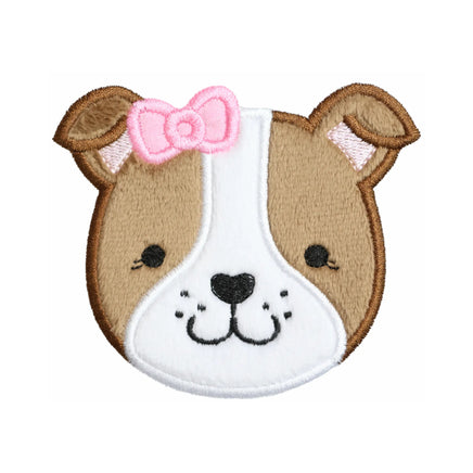 Bulldog puppy embroidered patch with a pink bow, tan plush face, white forehead stripe and muzzle, black stitched eyes and heart shaped nose, and brown satin stitched outline on a white background.