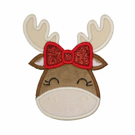 Christmas moose face appliqué patch with textured brown fabric, cream antlers and muzzle, closed black embroidered eyes with eyelashes, and a small smile. A red glitter bow with red embroidered outlines sits between the antlers. Photographed on a white background.