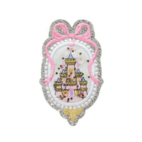 Princess castle shaker embroidery patch featuring a glitter silver scalloped frame, pink bow detail, and embroidered fairy tale castle with loose sparkle confetti inside. This handmade princess castle appliqué patch is shown isolated on a white background and is designed for kids clothing, dresses, backpacks, jackets, and craft projects.