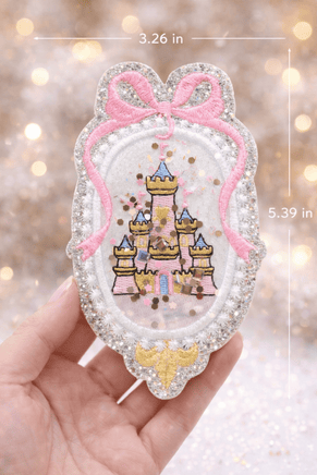 Princess castle embroidery patch with glitter silver scalloped edge and pink bow detail, shown with size measurements for scale. This fairytale castle appliqué patch is designed for children’s clothing, backpacks, and craft projects.