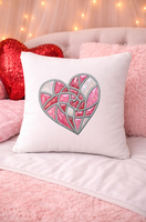 Decorative pillow with a heart design on a pink couch with a heart-shaped pillow and fairy lights in the background.