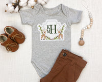 Rustic woodland monogram embroidered patch displayed on baby bodysuit outfit, personalized deer crest applique patch for baby shower gifts and boutique clothing